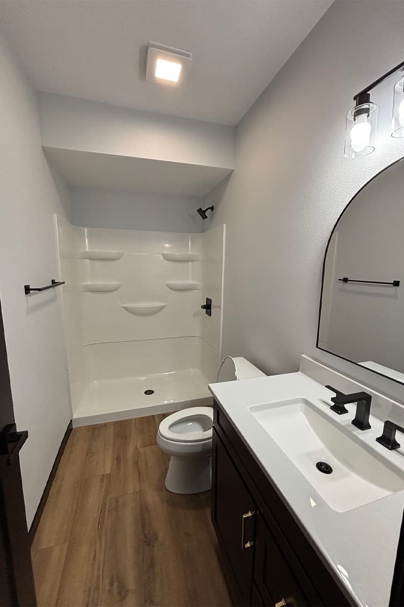 Bathroom with wooden floor, sink, toilet and shower
