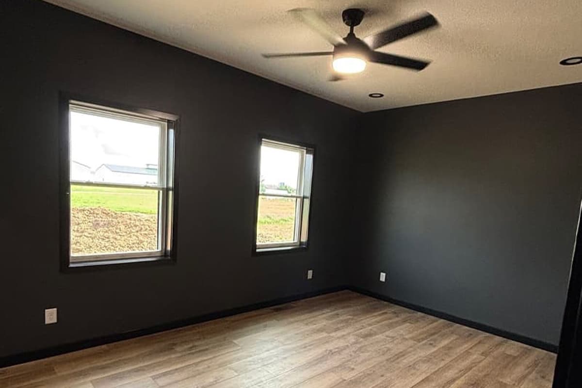 Room with wooden floor, black walls and windows