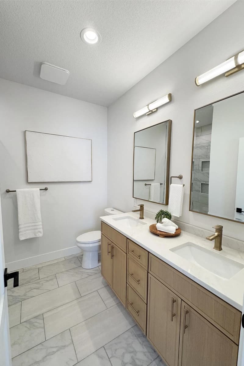 Bathroom with double sinks, double mirrors and toilet
